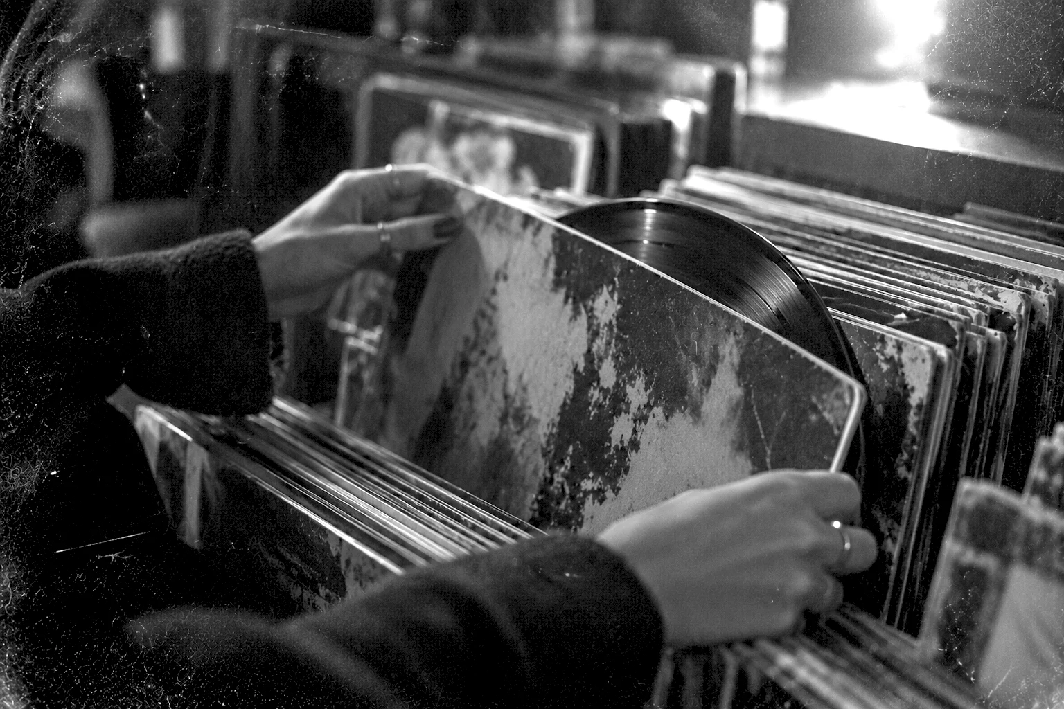 Hands flipping through record sleeves in a crate
